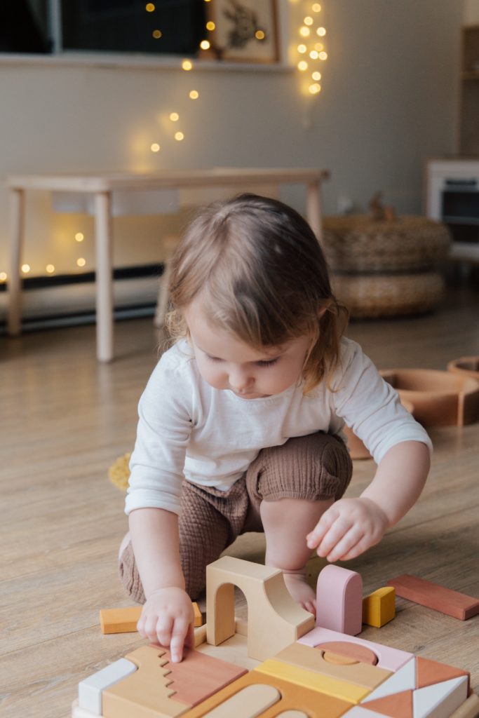 Little girl playing with wooden blocks on the floor